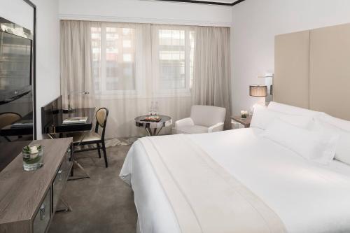 a hotel room with a large white bed and a table at Meliá Castilla in Madrid