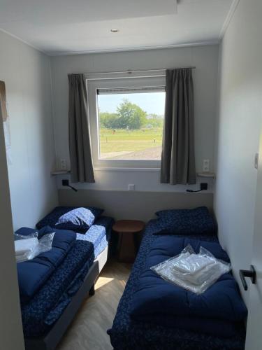 two beds in a small room with a window at Waddenlodge Exclusive in Harlingen