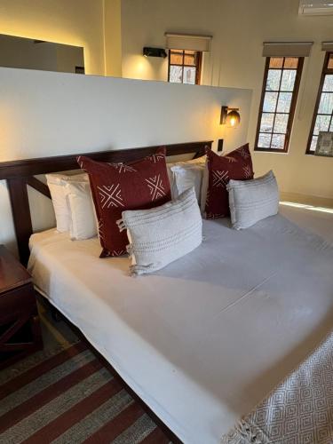 a large white bed with red and white pillows at Tulani Boutique Lodge - Includes Game drives and Meals in Grietjie Game Reserve