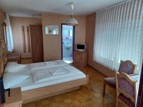 a bedroom with a large white bed and a television at Adler Gaststube Hotel Biergarten in Bad Rappenau