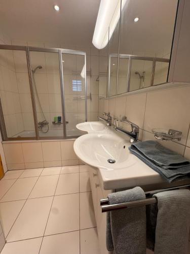 a white bathroom with two sinks and a shower at Tgèsa Staziun in Sedrun