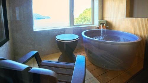 a large tub in a bathroom with a window at Livemax Resort Mihara Onsen Seafront in Mihara