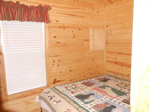 1 dormitorio con 1 cama en una habitación de madera con ventana en Oakzanita Springs Camping Resort Cabin 1 en Descanso