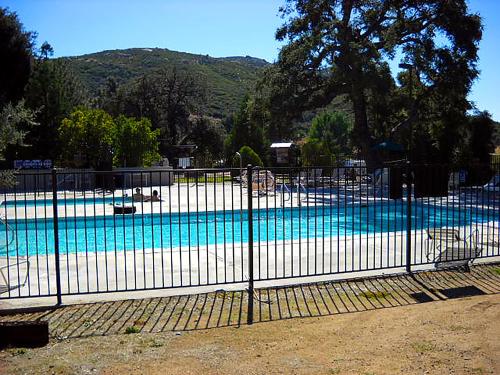a fence around a swimming pool with a swimming pool at Oakzanita Springs Camping Resort Cabin 1 in Descanso