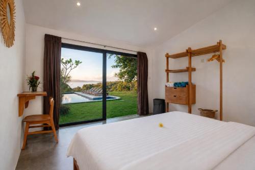 a bedroom with a white bed and a large window at Villa Panorama in Nusa Penida