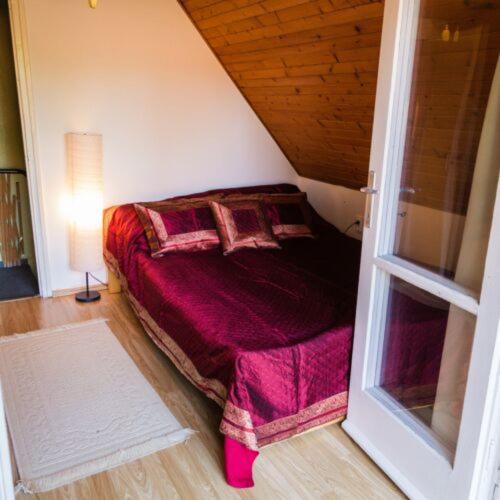 a bedroom with a bed with a purple blanket at Vár-Lak Nagymaros in Nagymaros