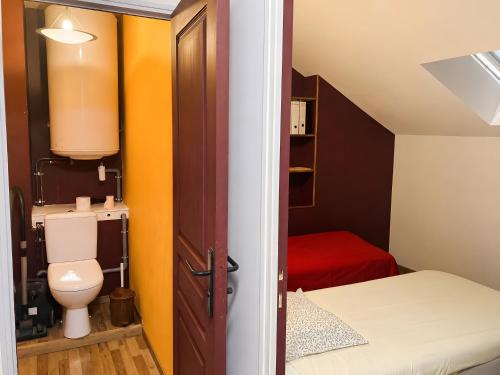 a small bathroom with a toilet and a bed at La Maisonnette in Les Andelys