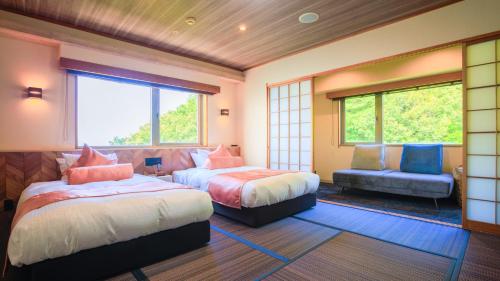 a bedroom with two beds and a couch and a window at Livemax Resort Mihara Onsen Seafront in Mihara