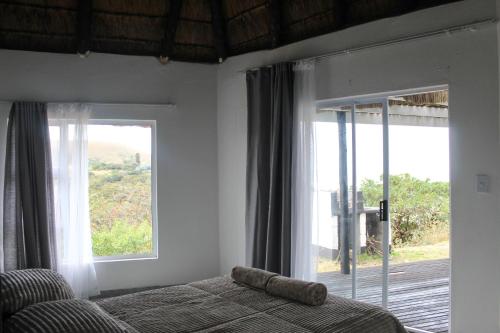 a bedroom with a bed and a large window at Hole in the Wall - Unit H1 in KuGqangushe