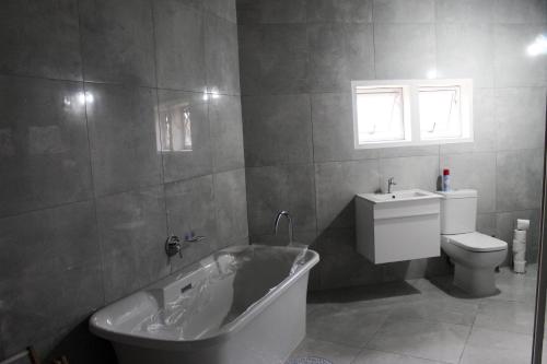 a bathroom with a tub and a toilet and a sink at Hole in the Wall - Unit H1 in KuGqangushe