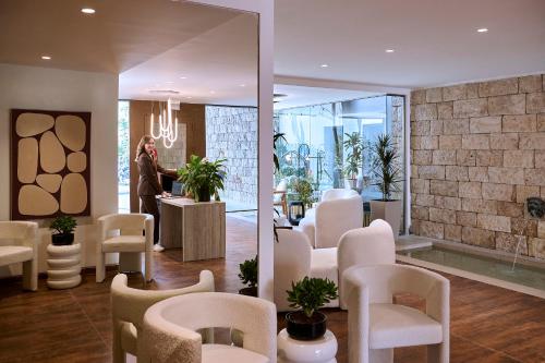 a salon with white chairs and a woman in a room at Zeus Piraeus Grand in Piraeus