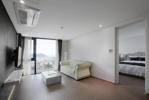 a white bedroom with a bed and a window at Eins Hotel in Seogwipo