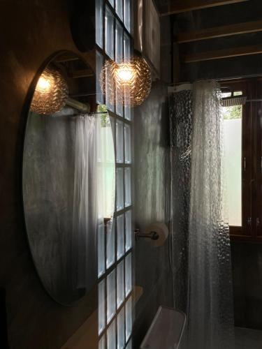 a bathroom with a mirror and a toilet and a window at Quiet Page CNX in Ban Phae Buak Ha