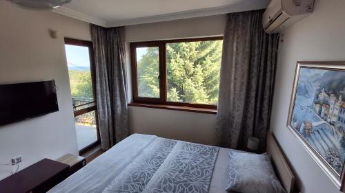 a bedroom with a bed and a large window at Villa Detelina Balchik in Balchik