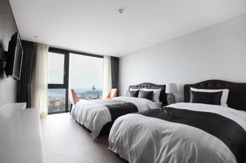 a hotel room with two beds and a large window at Eins Hotel in Seogwipo