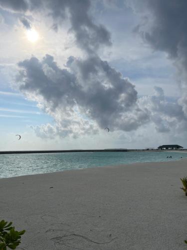 two kites flying over the water on a beach at Bahee Dé Lite in Kulhudhuffushi