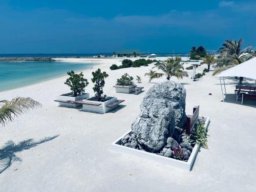 a beach with a large rock on the beach at Bahee Dé Lite in Kulhudhuffushi