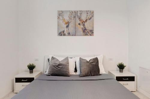 a white bedroom with a bed with two night stands at Casa Sole Porlezza in Porlezza