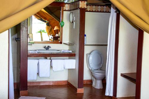 a bathroom with a toilet and a sink with towels at Sweetwaters Serena Camp in Nanyuki