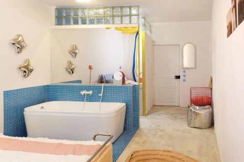 a bathroom with a white tub and blue tiles at Plumard in Arles