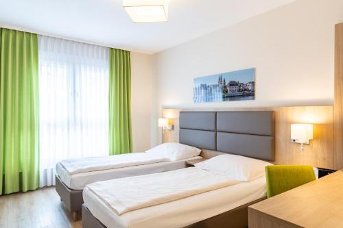 a hotel room with two beds and a table at City-Hotel Kurfürst Balduin in Koblenz