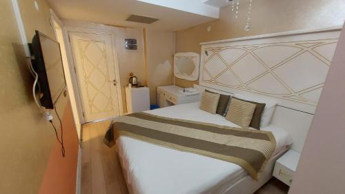 a small bedroom with a bed and a television at Aksu Otel in Aliağa