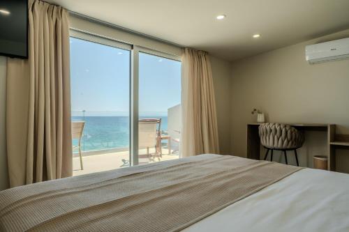 a bedroom with a bed and a view of the ocean at Amaltheia Beachfront Villas in Kypseli