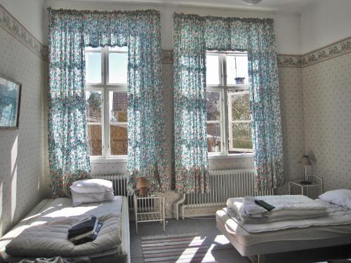 a bedroom with two beds and two windows at Tivedens Hostel-Vandrarhem in Karlsborg