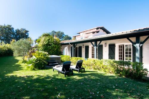 a house with two chairs and a table in the yard at Villa des Landes - Seignosse - Jacuzzi in Seignosse