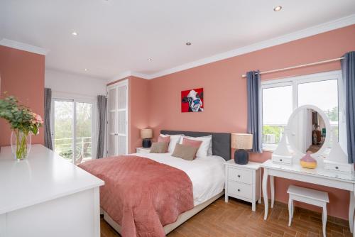 a bedroom with pink walls and a bed and a desk at Dois Moinhos Do Vento, Santo Estevão in Santo Estêvão