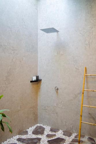 a shower in a bathroom with a shelf on the wall at Villa Mercure. Private villa. 2 en-suite bedrooms. in Amed