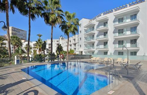 a swimming pool in front of a building with palm trees at SOL by Meliá Torremolinos Don Marco - Adults Recommended in Torremolinos