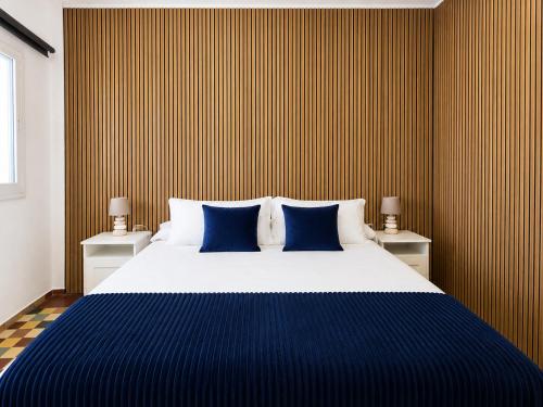 a bedroom with a large bed with blue pillows at Oasis Noalys in Sardina
