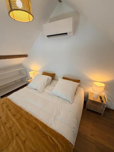 a bedroom with a large white bed with two lamps at Chez Mémé Cécile in Montluçon