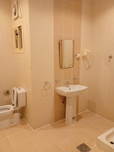 a bathroom with a toilet and a sink at شقق ليالي الشاطئ in Al Qunfudhah