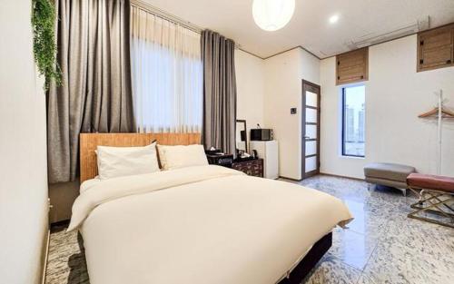 a bedroom with a large white bed and a living room at Jardin Hotel in Seoul