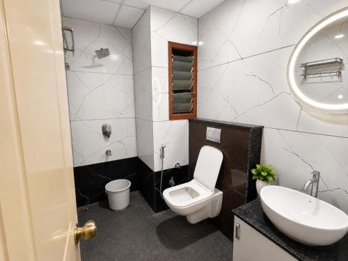 a bathroom with a toilet and a sink and a mirror at Sree Durga Hotel Ramsons International in Mysore