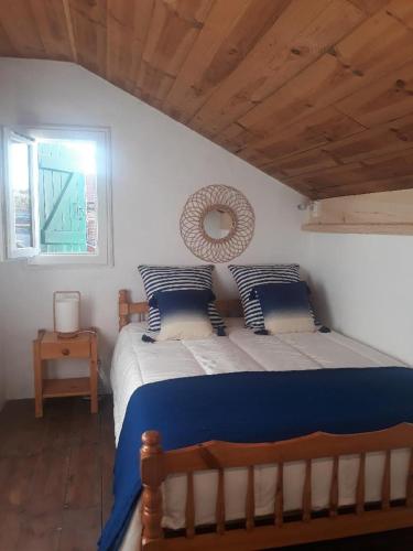 a bedroom with a large bed with blue and white pillows at La charmante Capbretonnaise in Capbreton