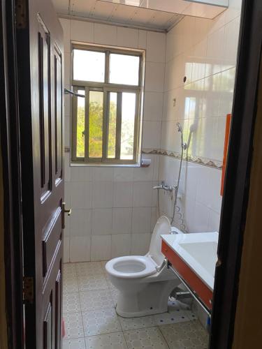 a bathroom with a toilet and a sink and a window at New Gold city hotel in Mwanza