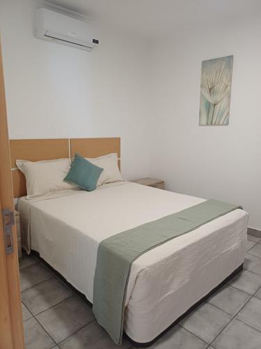 a bedroom with a large white bed with blue pillows at Madeira Pura in Calheta