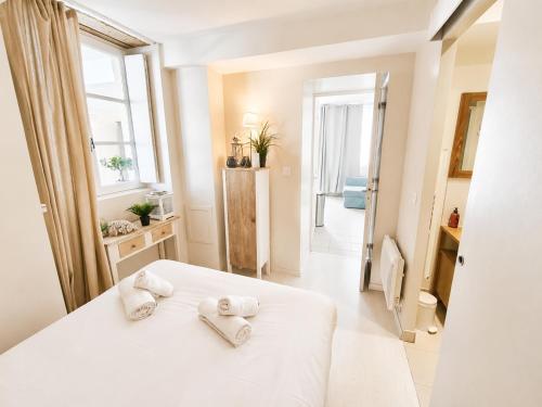 a bedroom with a white bed with towels on it at Apt duplex ou plain pied tout confort plein centre ville Bayeux proche commerces, restaurants, avec terrasse privative ou jardin commun aménagé clos, parking gratuit à proximité, proche plages du débarquement in Bayeux