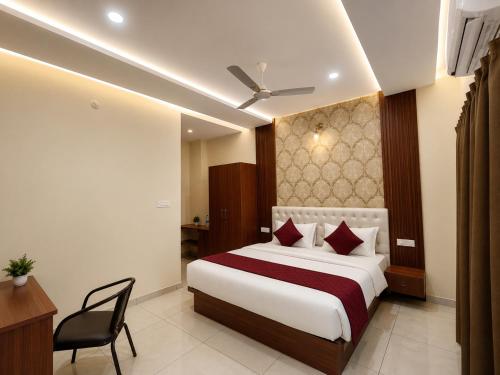a bedroom with a bed and a desk and a chair at Sree Durga Hotel Ramsons International in Mysore