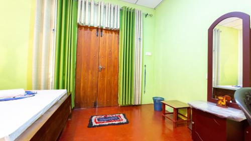 a bedroom with green curtains and a wooden door at N S K Green Villa in Sigiriya