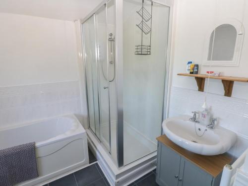 a white bathroom with a shower and a sink at Tor Cefn in Kidwelly