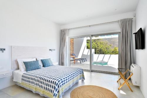 a white bedroom with a bed and a balcony at Theros Apartments 3 in Mylopotas