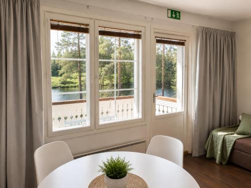 a living room with a table and chairs and windows at Aldeia Bianca Lake Resort & Italian Restaurant in Kerimäki