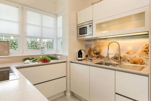 a kitchen with white cabinets and a sink at Ferienhäuser TraumZeit in Zingst