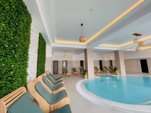 ein Pool in einem Hotel mit Stühlen und einer Hecke in der Unterkunft Pensiunea ROCA Maramures in Deseşti