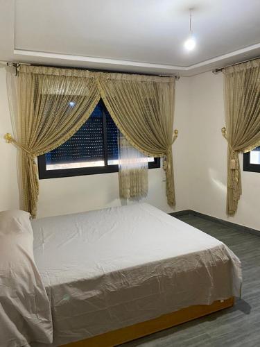 a bedroom with a bed and two windows at Appartement 1 in Al Hoceïma