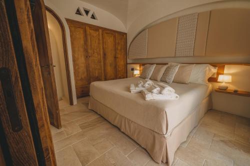 a bedroom with a bed with two dolls on it at Hotiday Elite Olea Sanctuary in Olbia